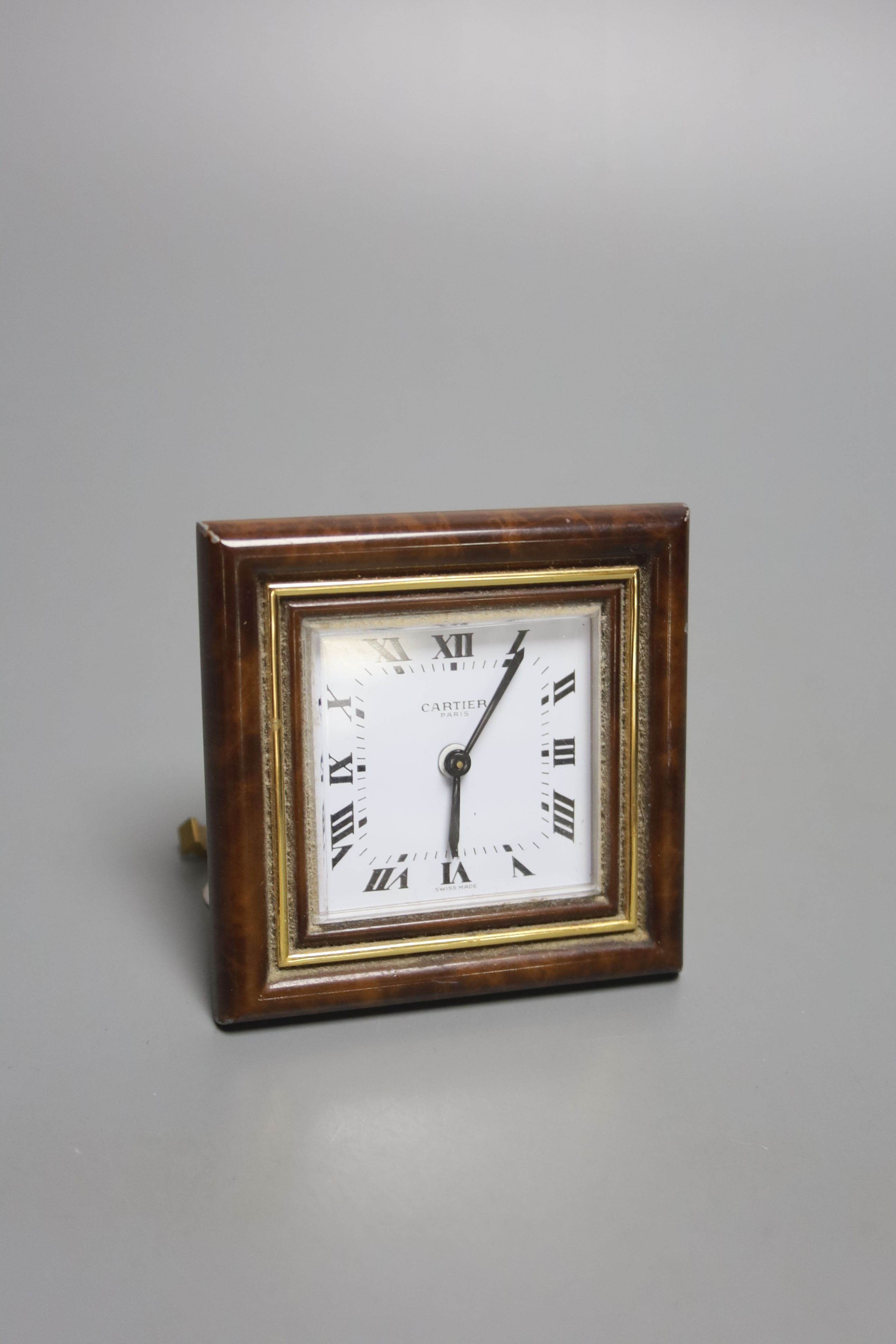 A gilt metal and faux tortoiseshell mounted Cartier travelling clock, with red Cartier pouch (small chips to border).